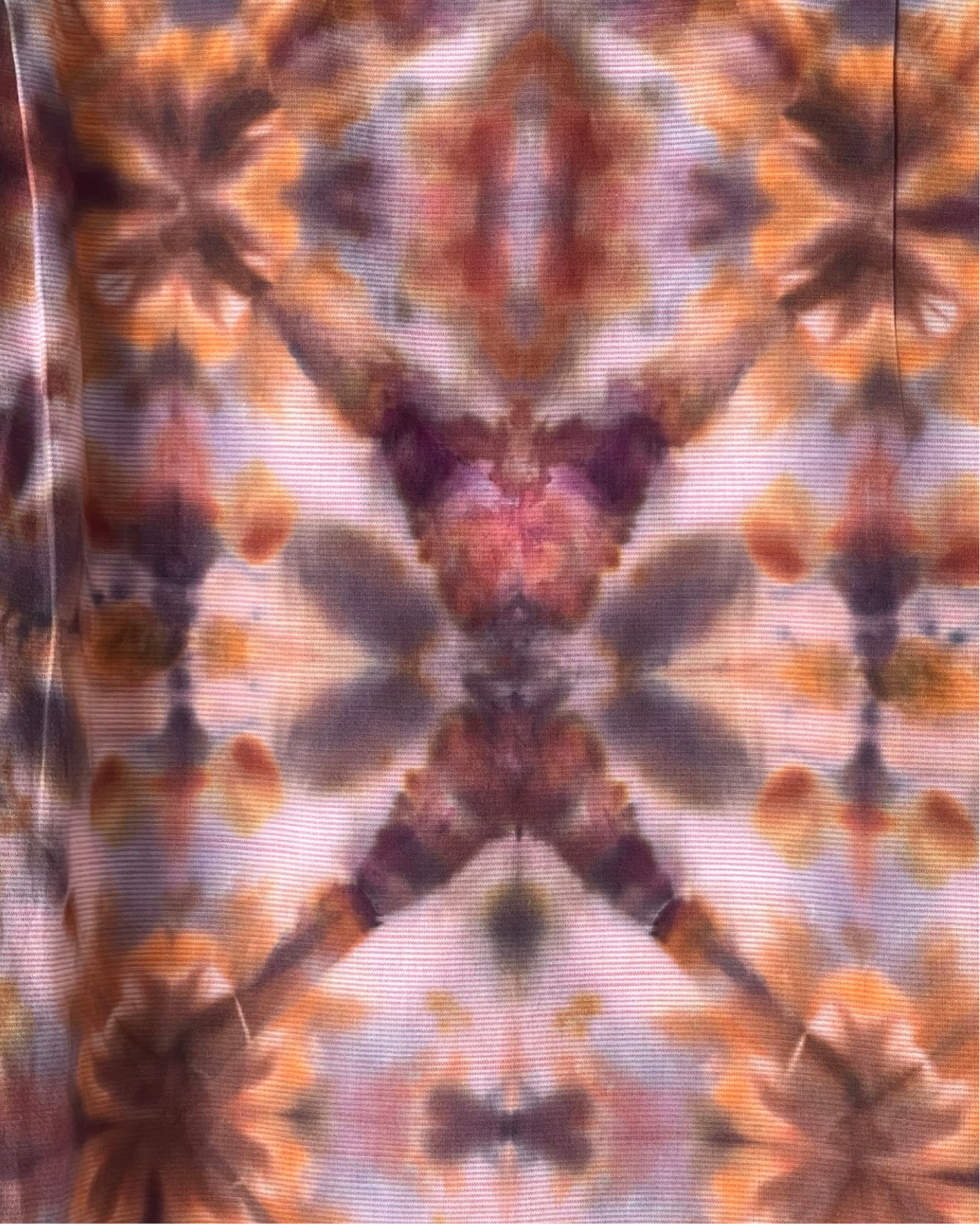 Tie-dye pattern with orange, brown, and purple colors on a fabric background