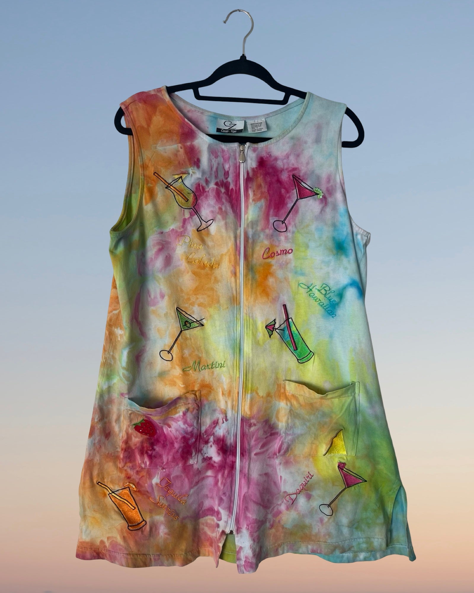 Colorful tie-dye sleeveless dress with drink graphics on a hanger against a gradient background
