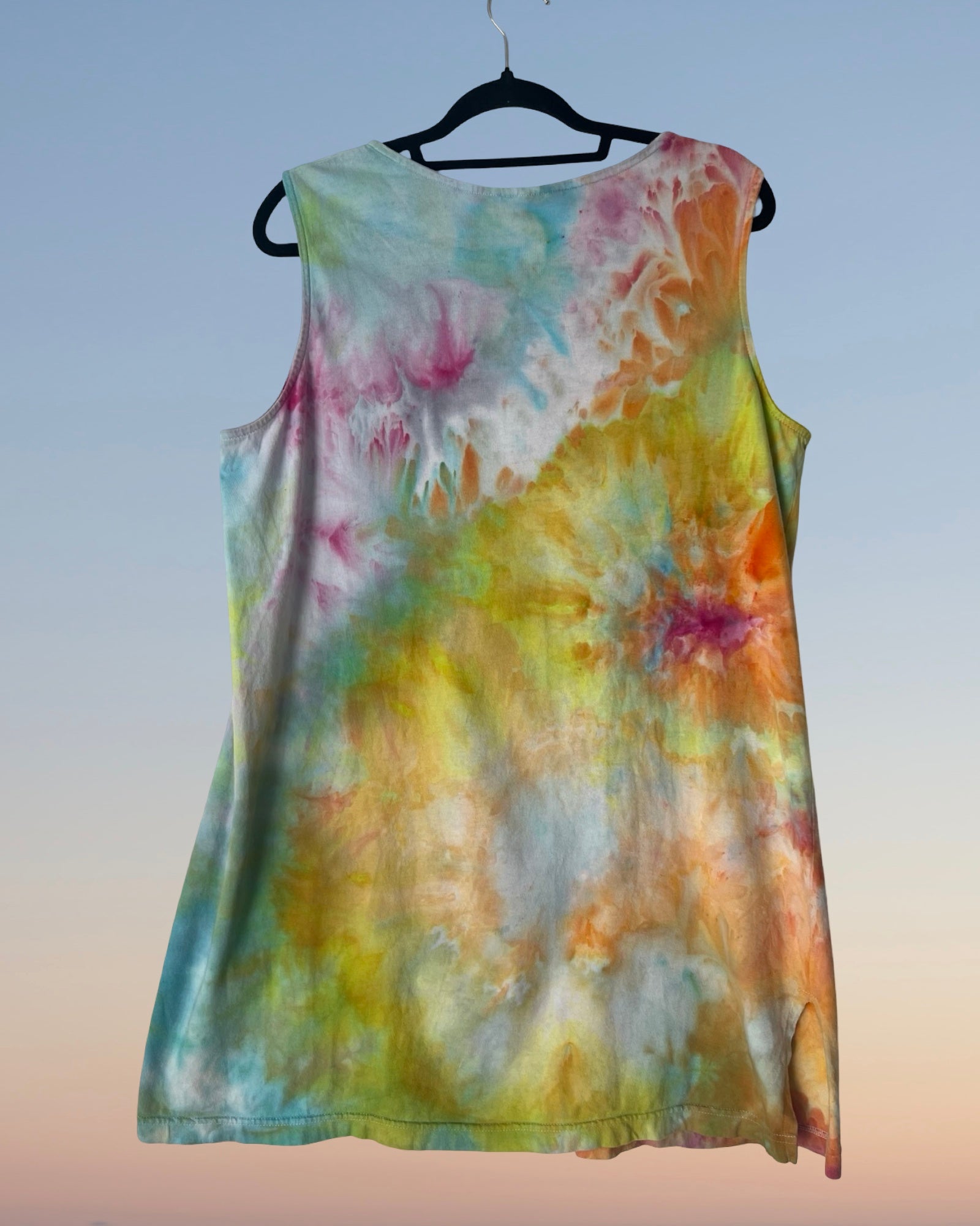 Colorful tie-dye sleeveless top on a hanger against a gradient background