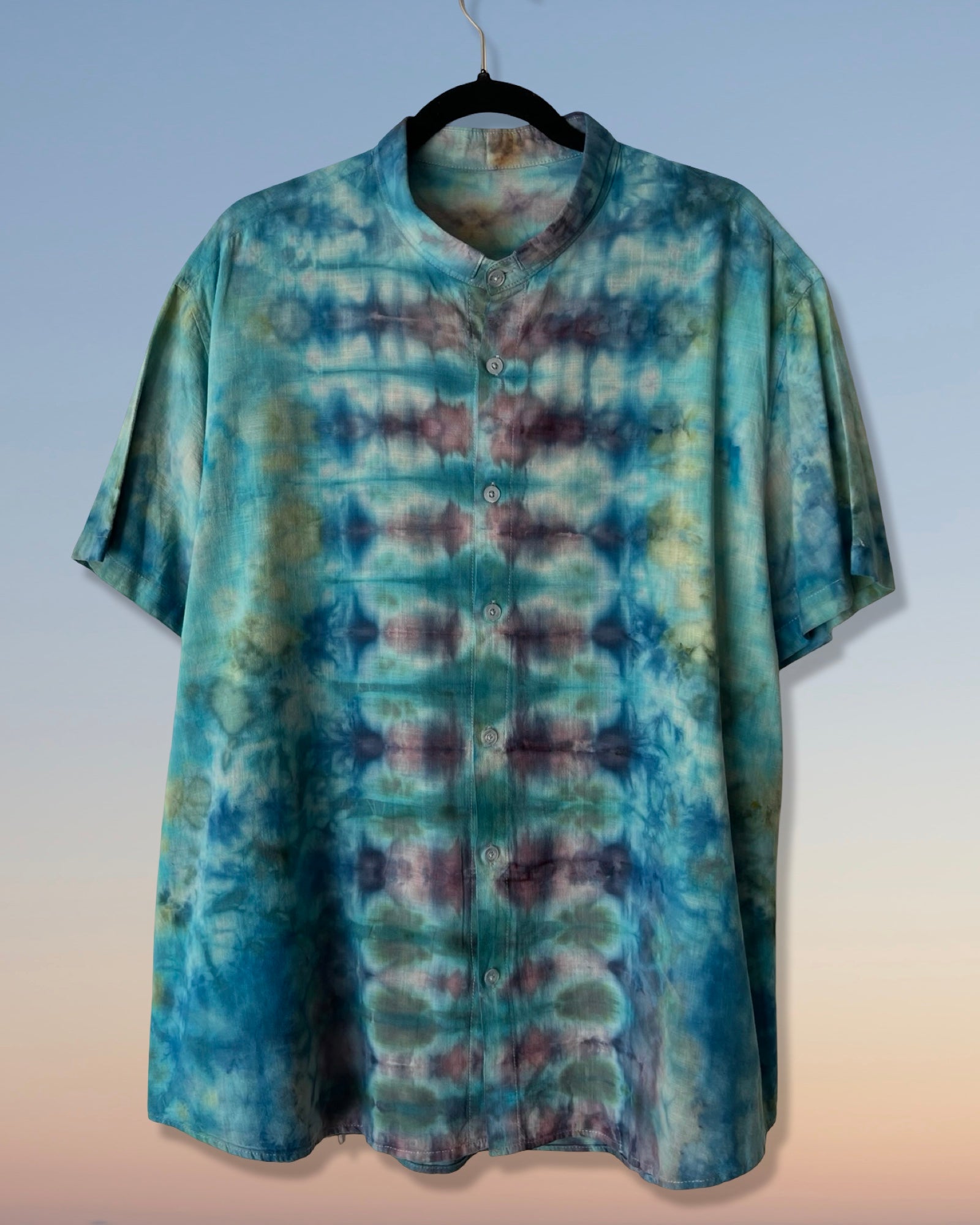 Tie-dye shirt on a hanger against a light blue wall