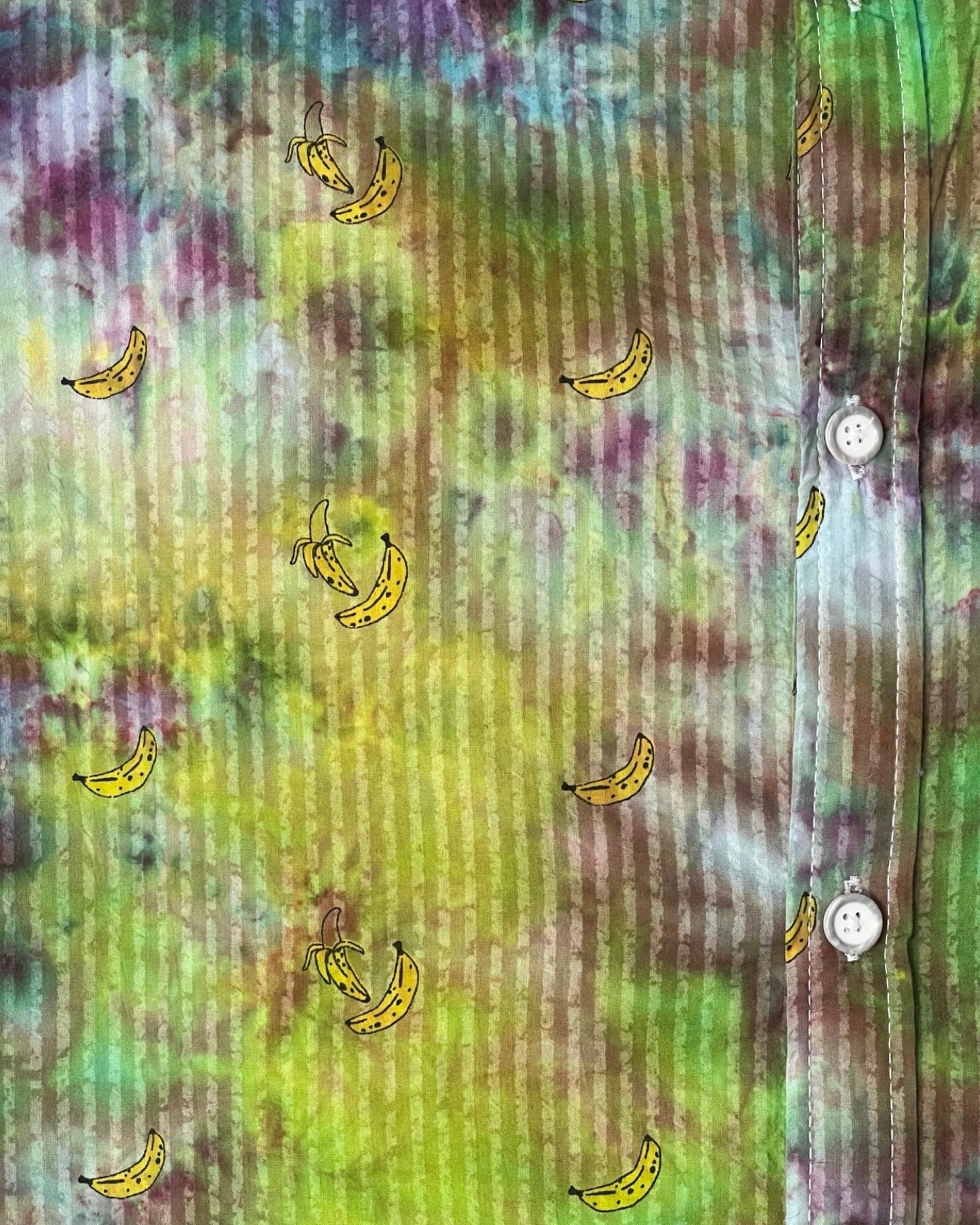 Colorful tie-dye shirt with small banana patterns on a multicolored background