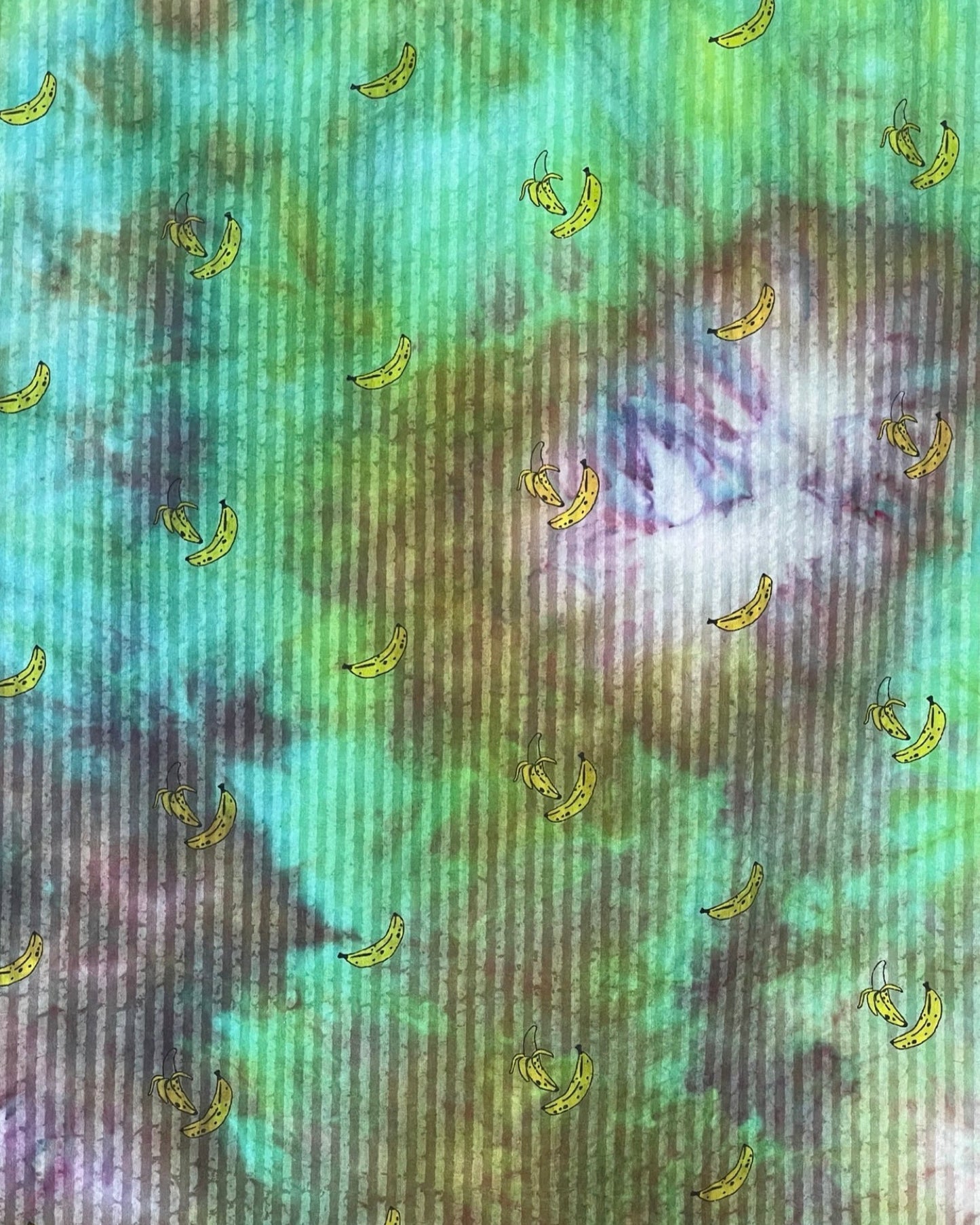 Tie-dye fabric with small banana patterns on a multicolored background