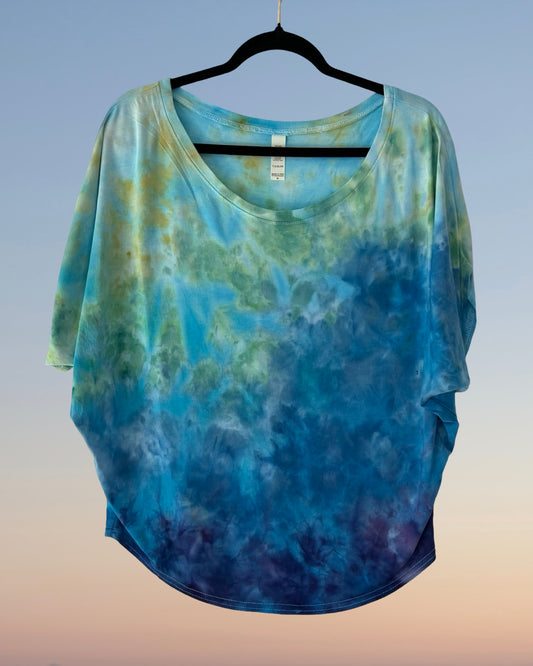 Blue and green tie-dye shirt on a hanger with a gradient background