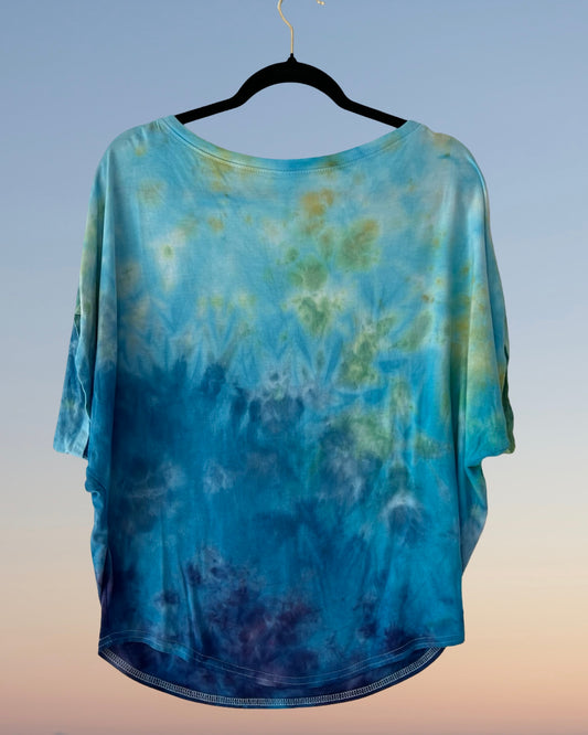 Blue tie-dye shirt on a hanger against a gradient background