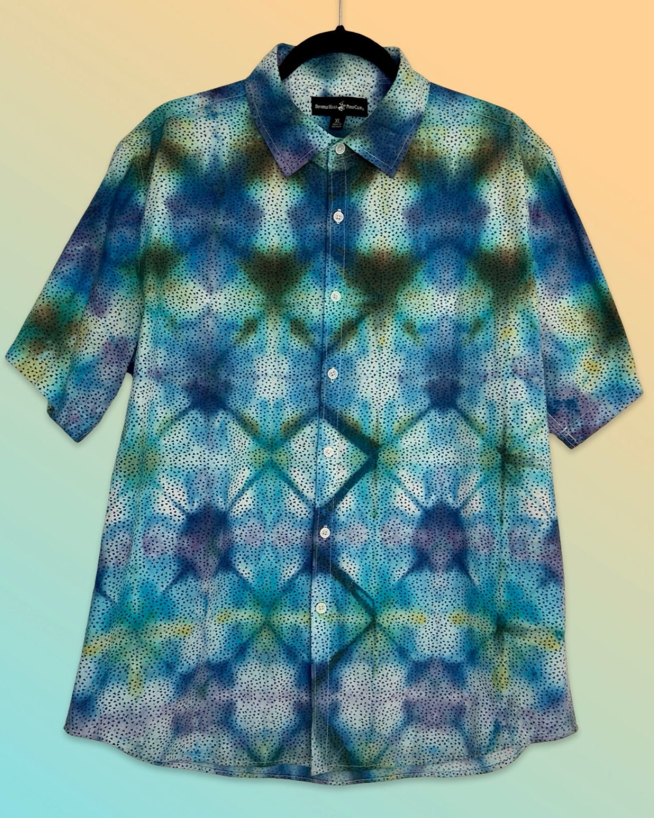 Blue and green tie-dye shirt on a hanger with a gradient background