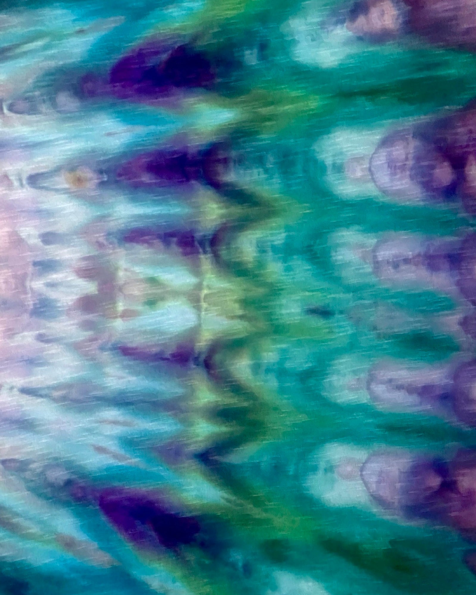 Close-up of tie-dye fabric with green, purple, and blue patterns