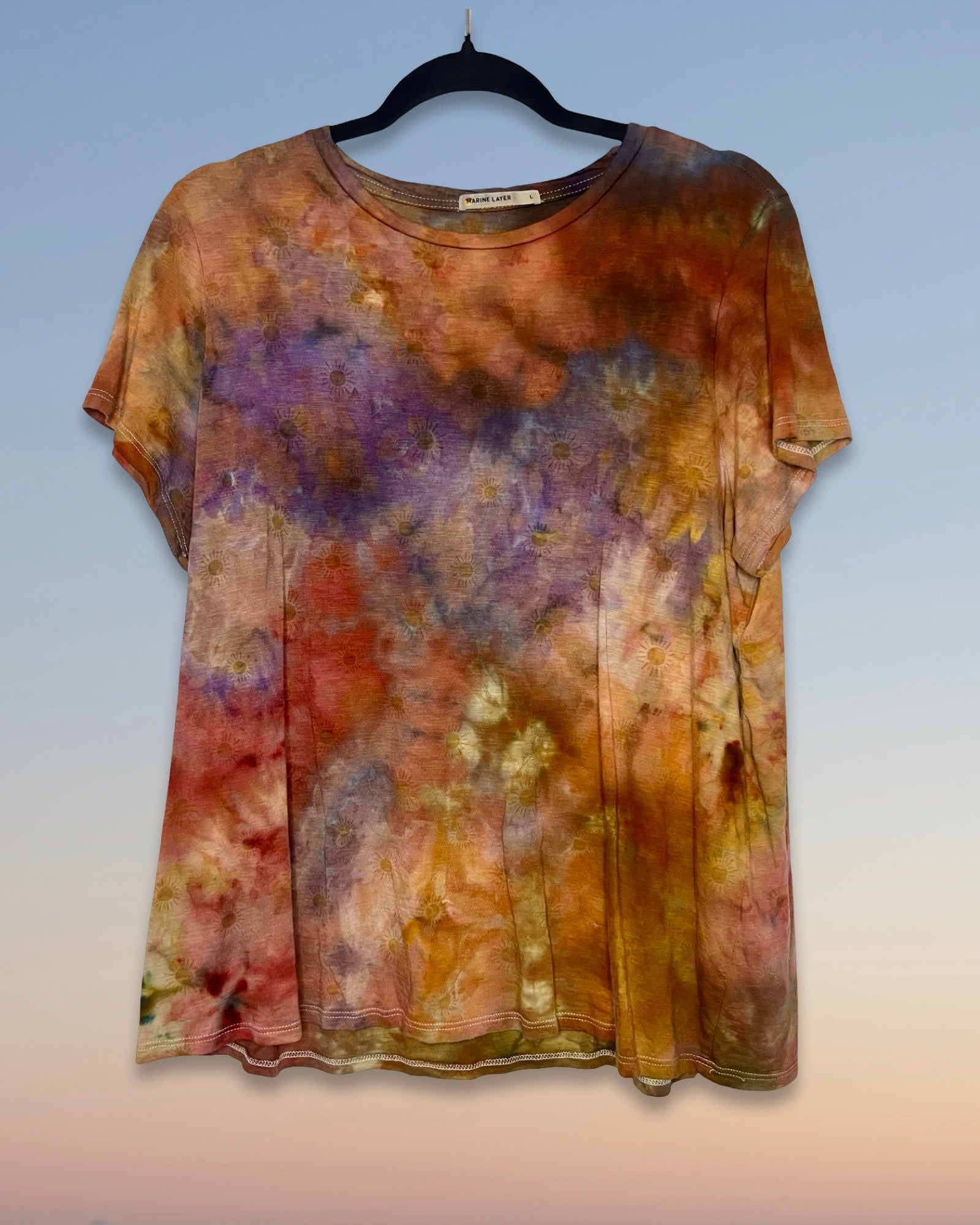 Multicolored tie-dye shirt on a hanger against a gradient background