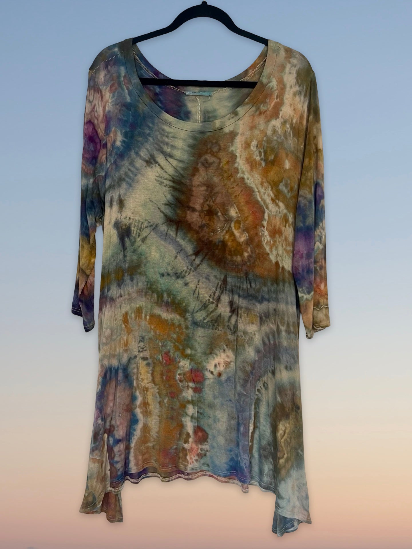 Multicolored tie-dye dress on a hanger against a light background
