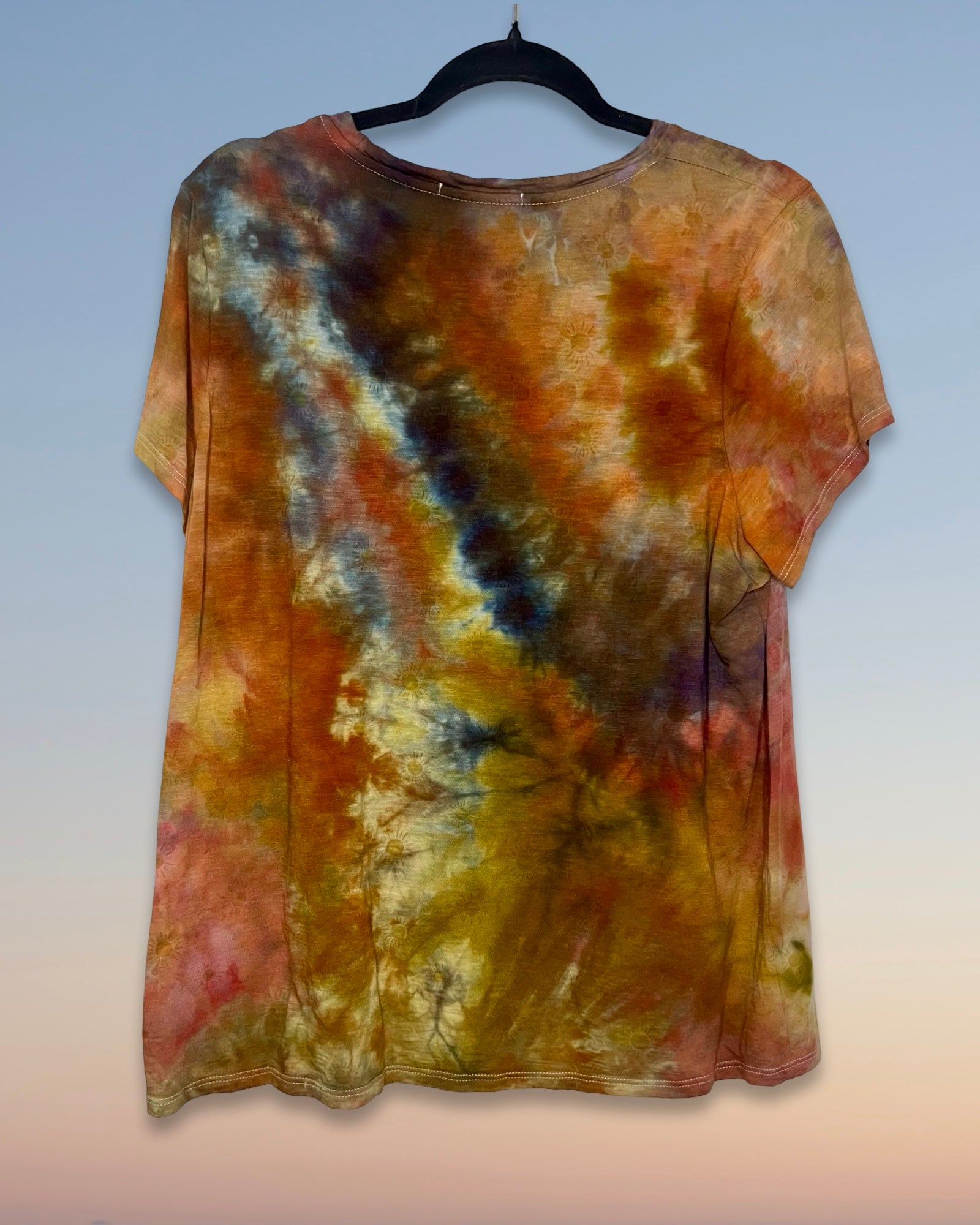 Tie-dye shirt on a hanger with a gradient of colors against a light background
