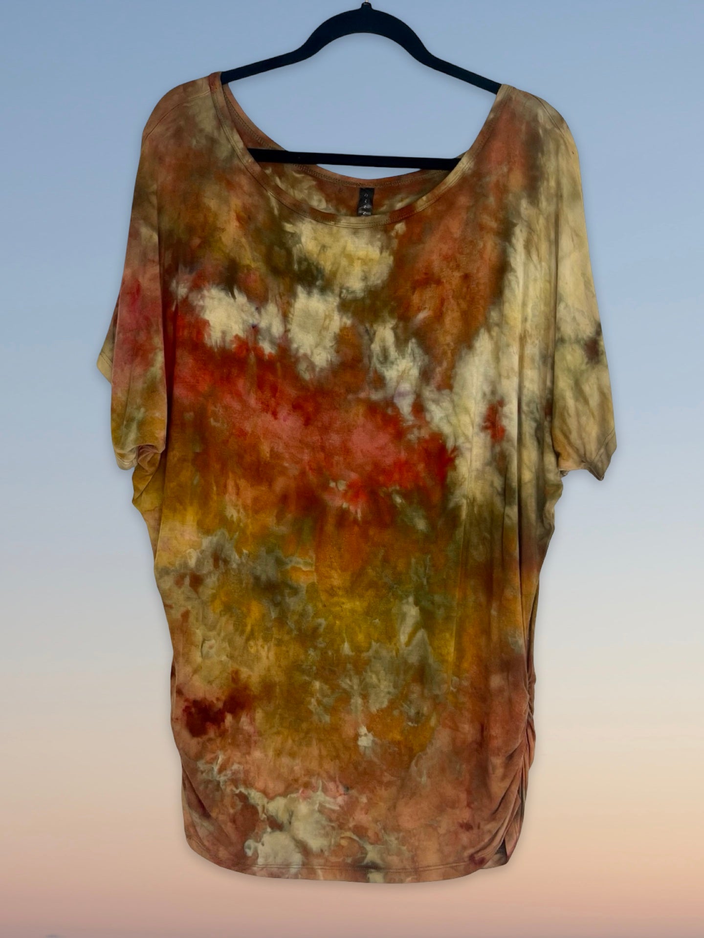 Multicolored tie-dye shirt on a hanger against a light blue background