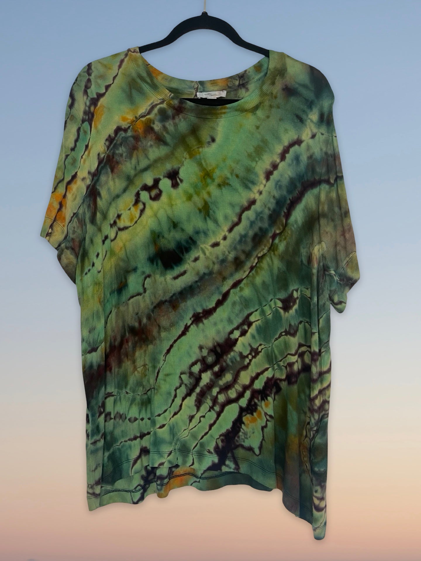 Tie-dye shirt on a hanger with a light blue background