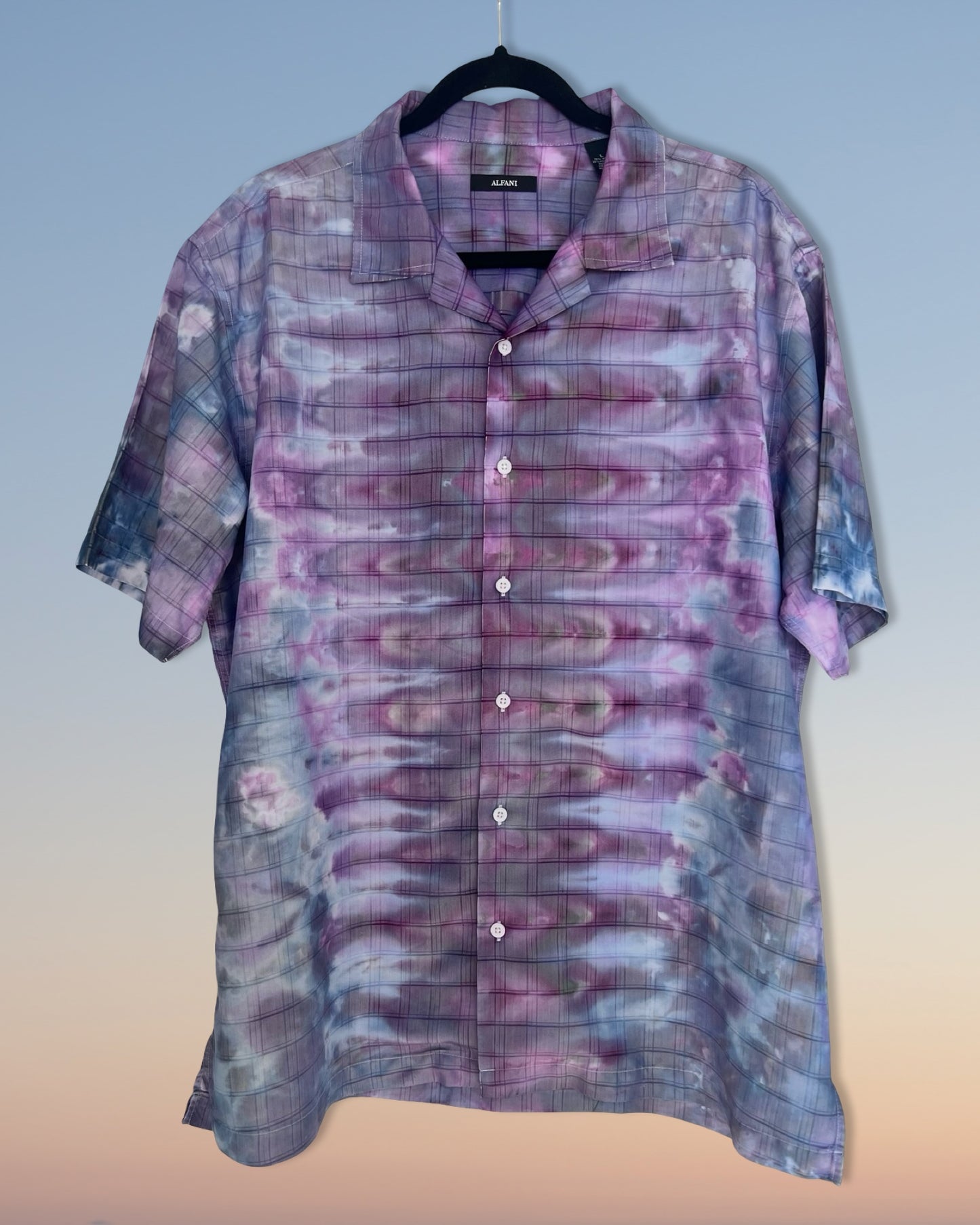 Short-sleeve shirt with a tie-dye pattern on a hanger against a gradient background