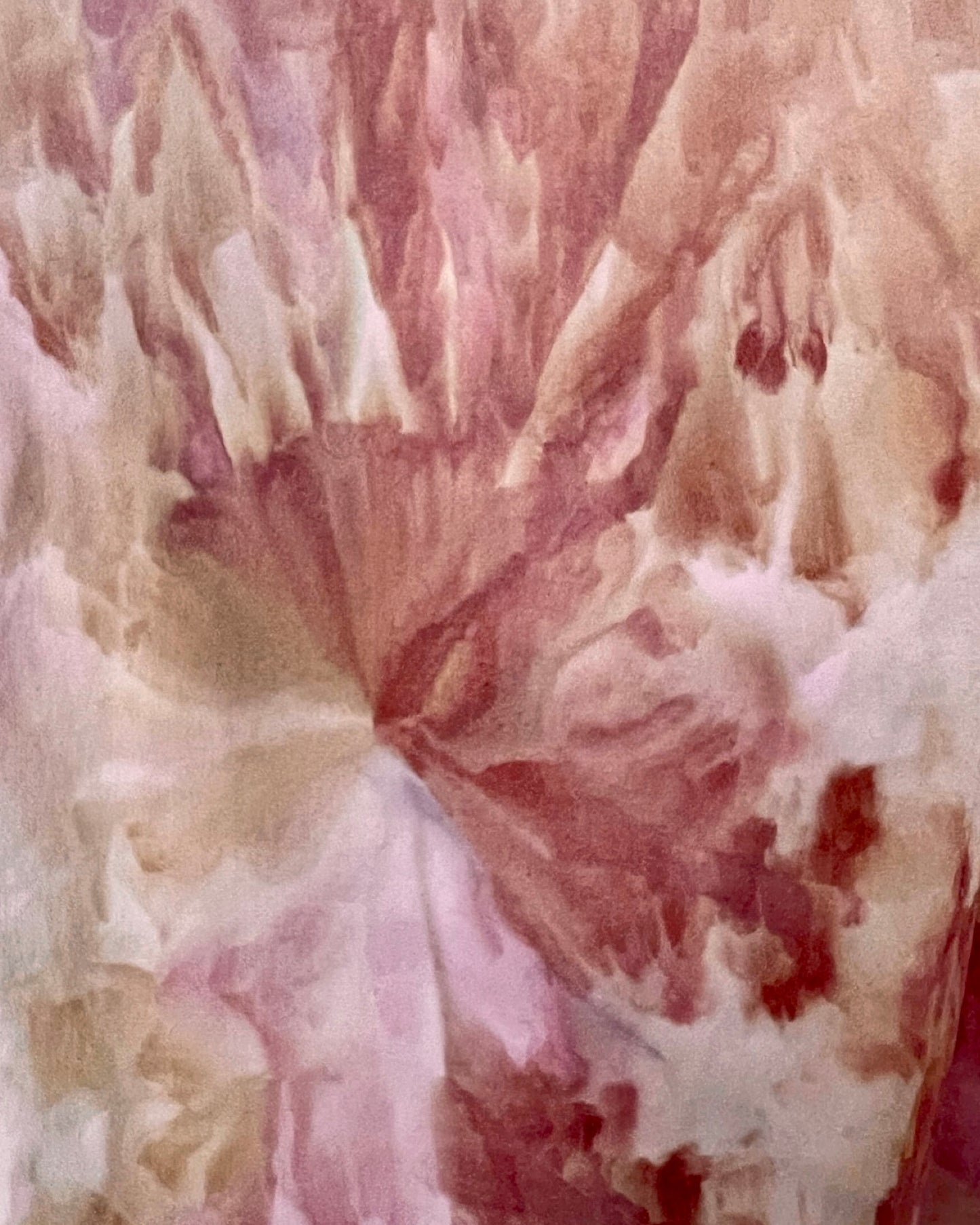 Close-up of ice dyed fabric with a swirling pattern in pink, red, and beige.