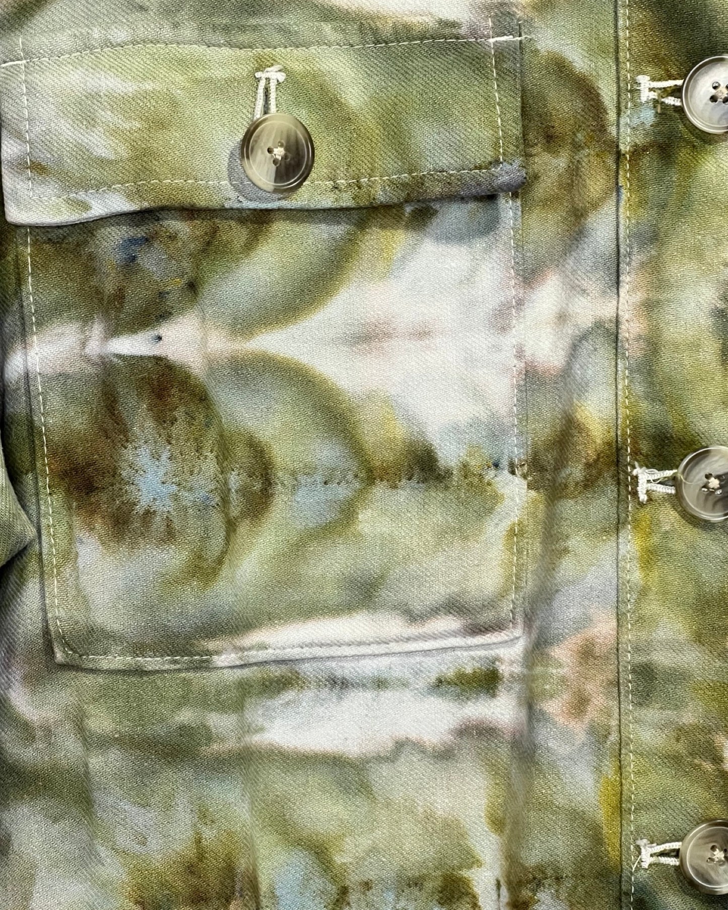 Close-up of a camouflage-tie dye jacket with button details