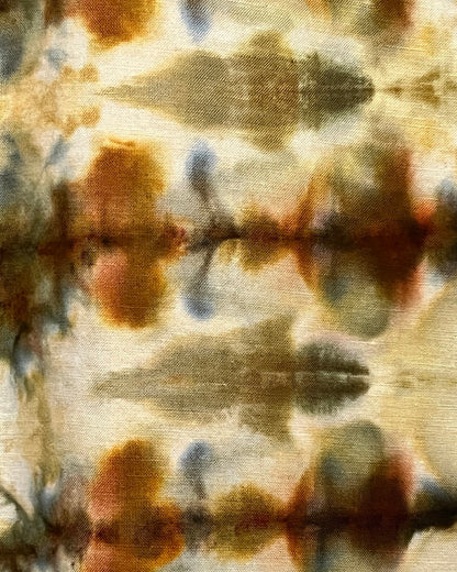 Abstract tie-dye pattern with brown, blue, and beige colors on a fabric background.