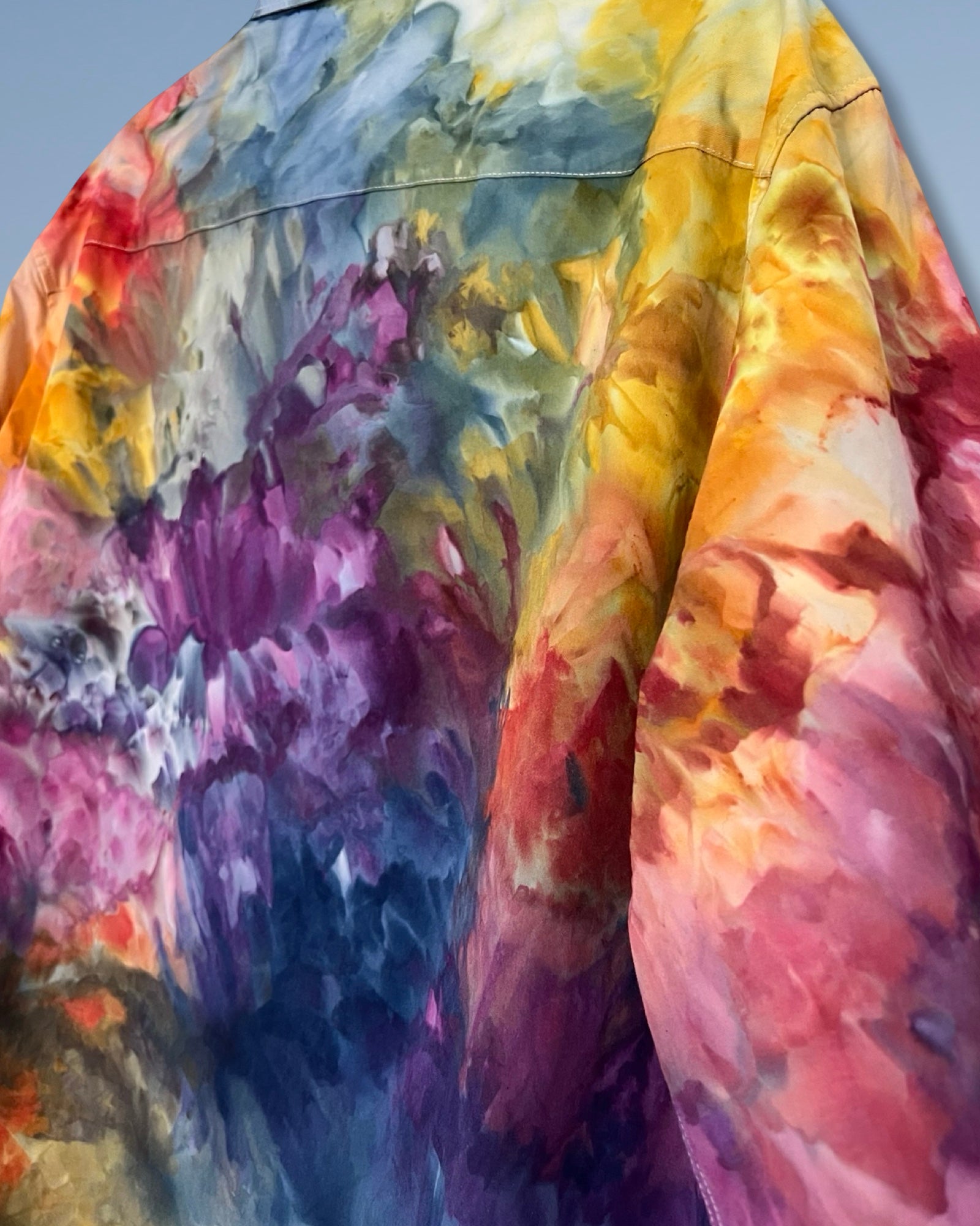 Colorful abstract pattern on a garment with a gradient of yellow, orange, pink, purple, and blue.