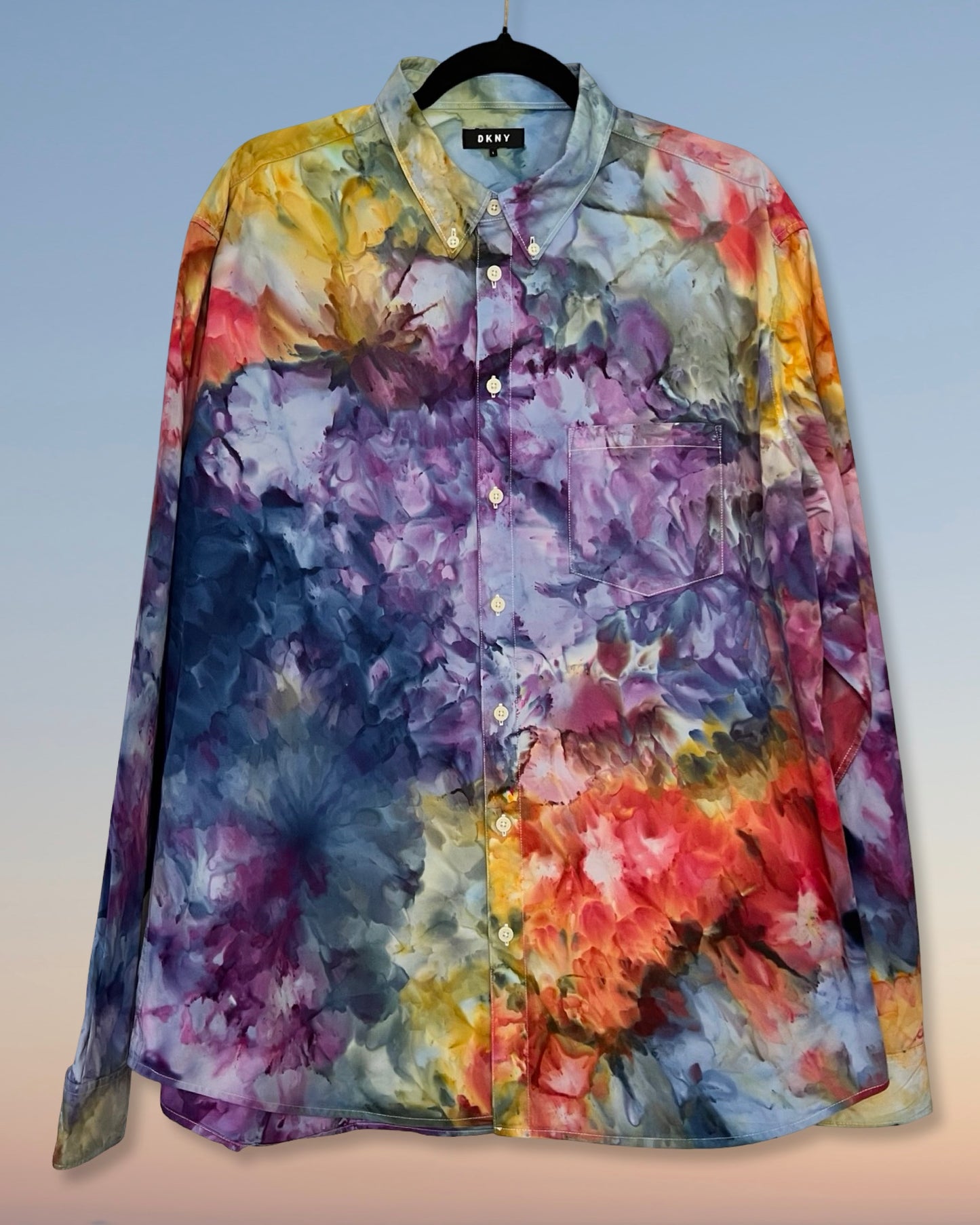 Colorful tie dye floral-patterned shirt on a hanger against a gradient background