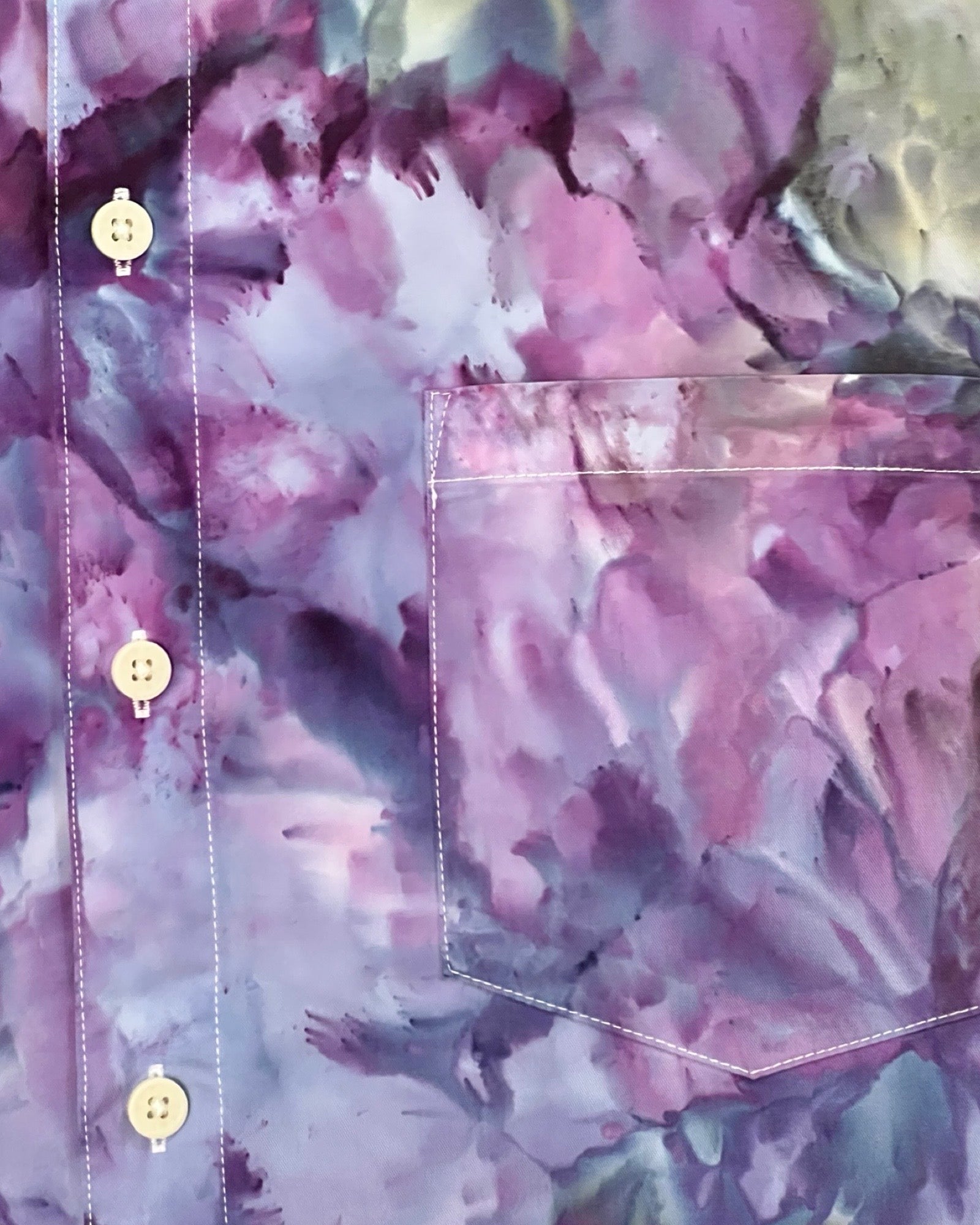Close-up of a floral-patterned tie dye shirt with a pocket and buttons.