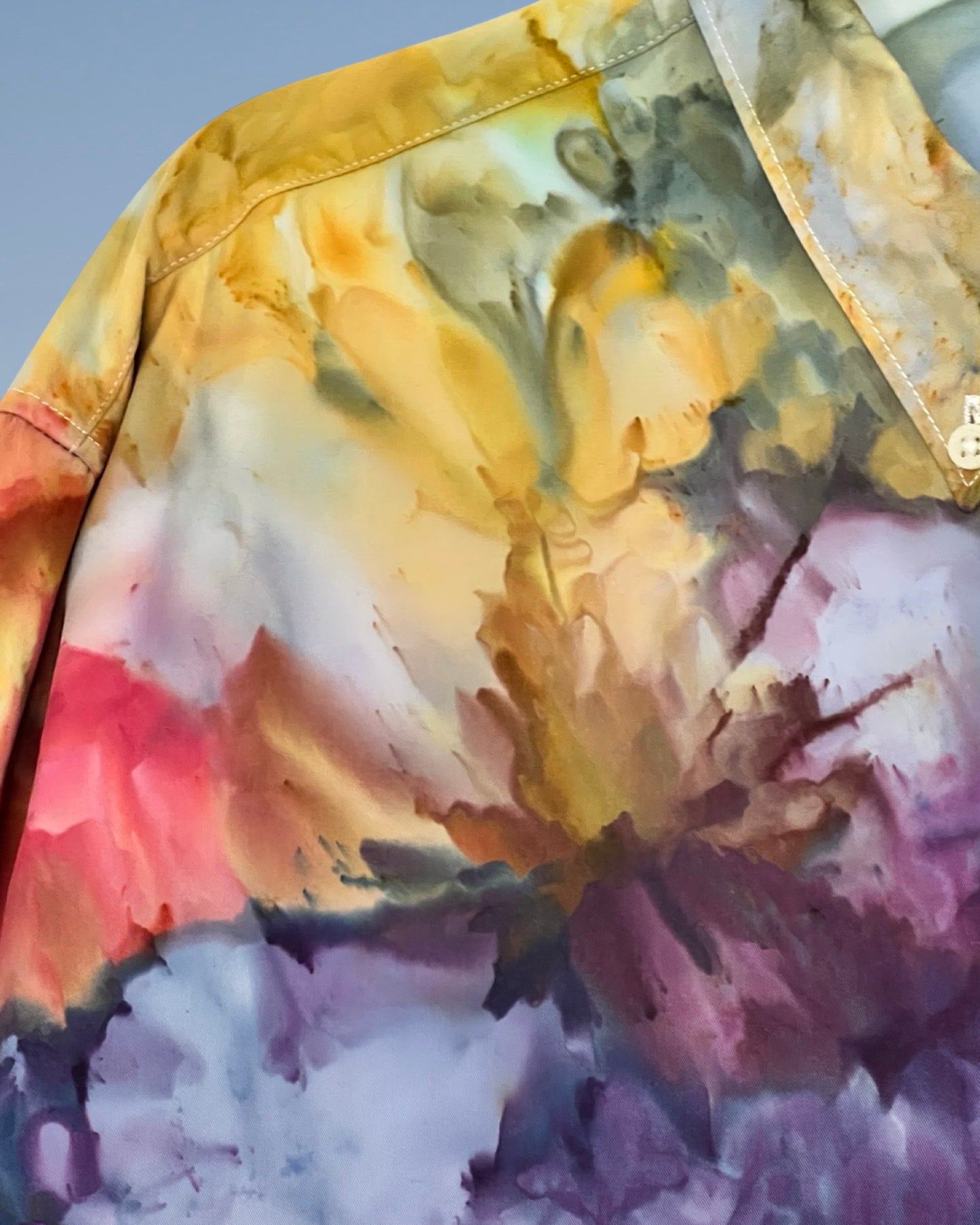 Close-up of a tie-dye shirt with multicolor patterns on a plain background