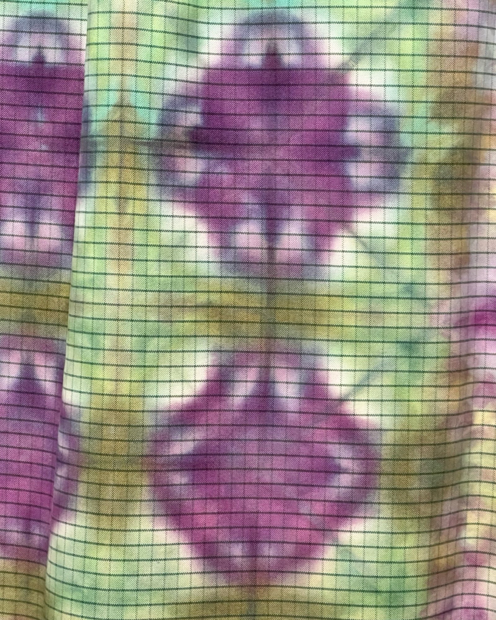 Close-up of a fabric with purple floral pattern on a green background