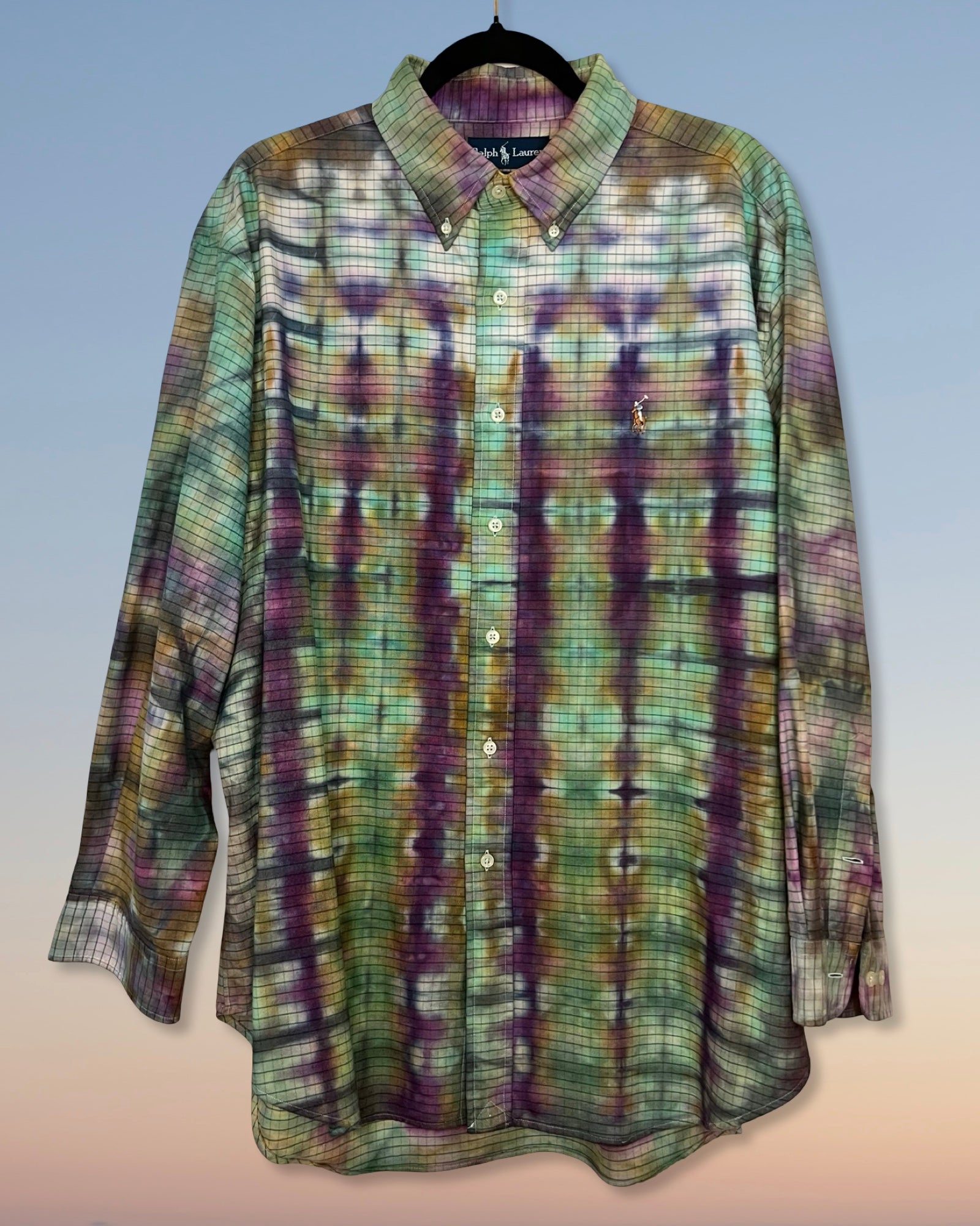Tie dyed plaid shirt with purple and green pattern on a light gray background