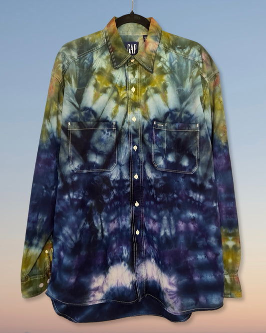 Tie-dye shirt on a hanger with a gradient of blue, green, and yellow colors.