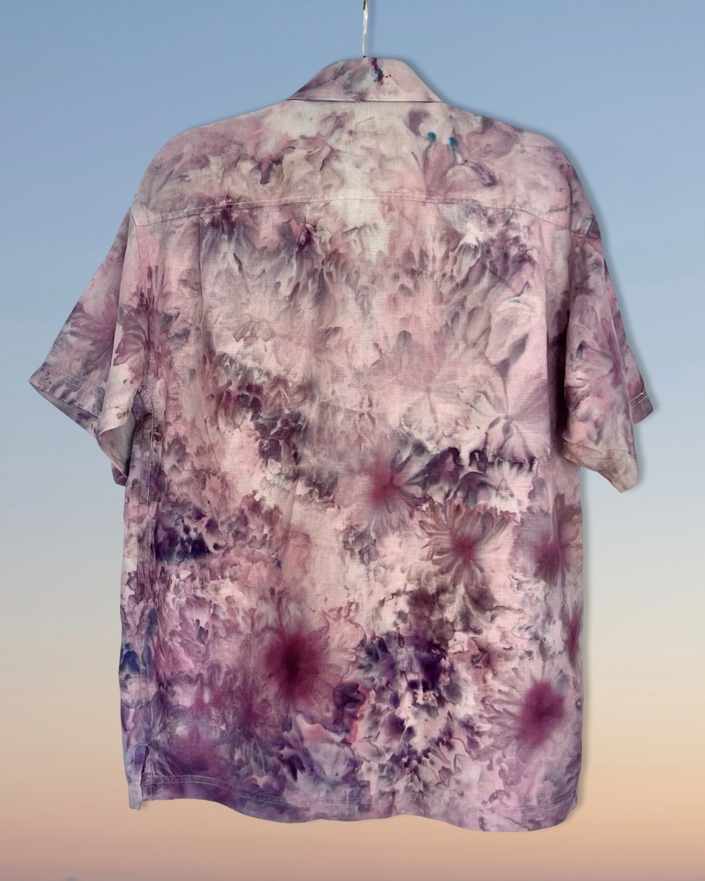 Floral patterned ice dyed shirt on a hanger against a gradient background