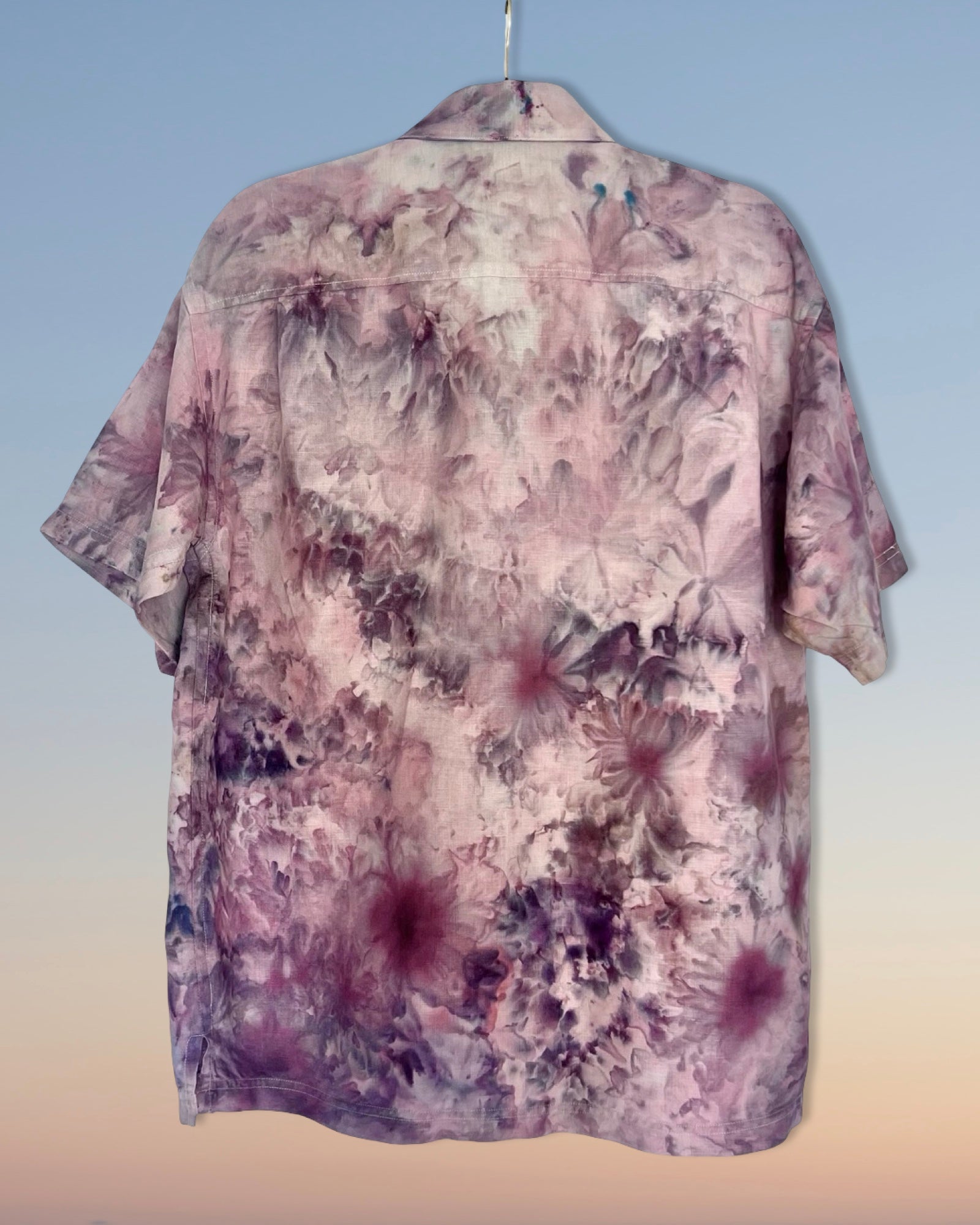 Floral patterned ice dyed shirt on a hanger against a gradient background