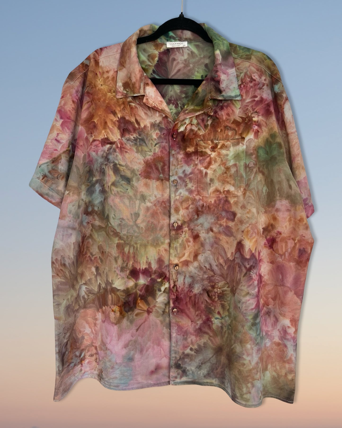 Floral patterned ice dyed shirt on a hanger with a gradient background